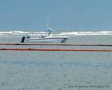 Small boat at sea near oil spill booms.jpg