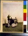 Four_immigrants_and_their_belongings,_on_a_dock,_looking_out_over_the_water;_view_from_behind.jpg