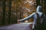 Person_with_Backpack_and_Grey_Hoodie_Hitchhiking_on_Road.jpg