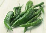 Long-green-chili-peppers-resting-on-wooden-board-surface.jpg