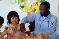 US_Navy_090301-N-2610F-007_Boatswain's_Mate_3rd_Class_Barn_Henderson,_from_Chicago,_opens_a_can_of_apple_juice_for_a_child_in_the_Kodomono-Ie_Children's_Home_during_a_community_service_project.jpg