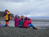 Children sit on the beach and watching the horizon with binoculars.jpg