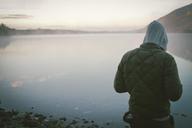 Person_in_Jacket_with_Hood_Standing_by_Lake.jpg