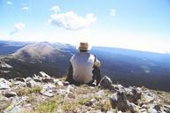 Man_Sitting_on_a_Mountain_Overlooking_a_Valley.jpg