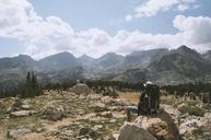 Hiker_with_Backpack_Sitting_on_a_Rock_Overlooking_Mountains.jpg