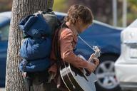 Man_carrying_guitar_and_backpack_walking_along_sidewalk_in_Berkeley.jpg